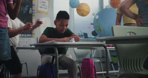 Sad Elementary School Student Crying While Classmates Bullying Him Throwing Papers