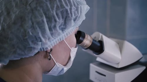 Doctor in Hospital Laboratory Looking Through Microscope