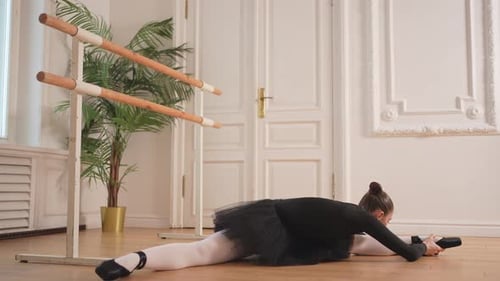 Woman Stretches Legs in Ballet Split Exercise