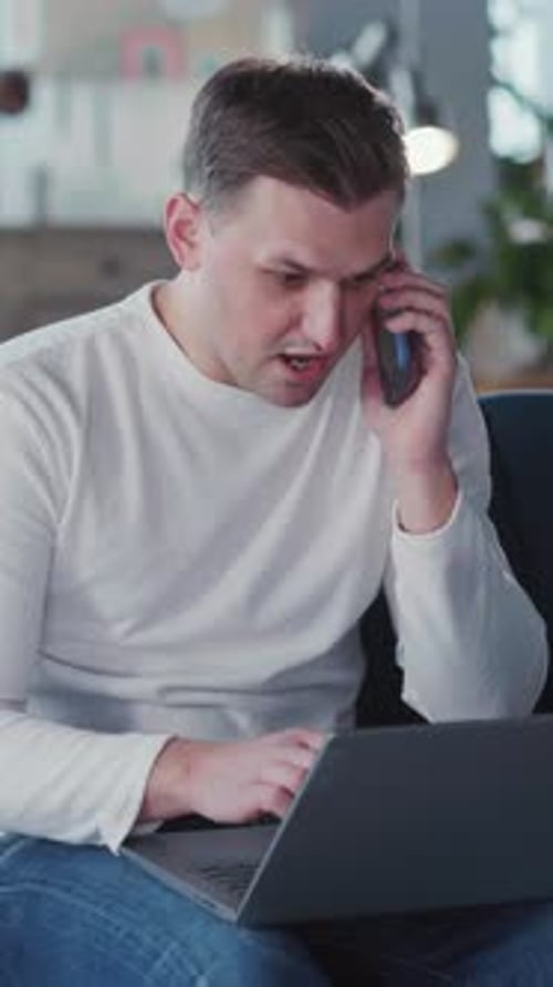 Man Talking on Phone While Using Computer at Home