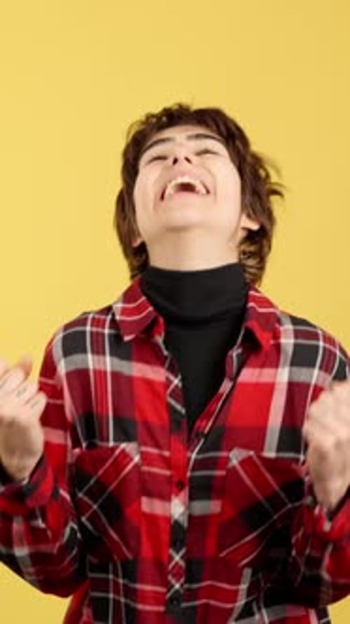 Person Smiling and Celebrating Success on Yellow Background