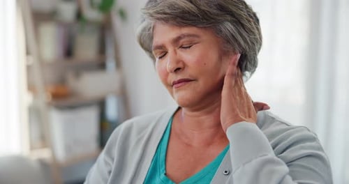 Senior Woman Rubbing Aching Neck Indoors