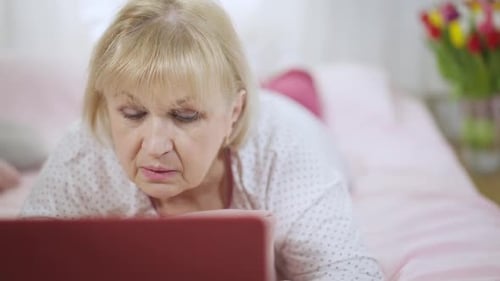 Senior Woman Using Laptop on Bed