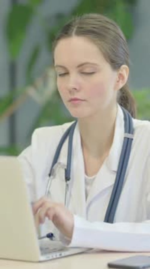 Smiling Young Woman Doctor Typing on Laptop