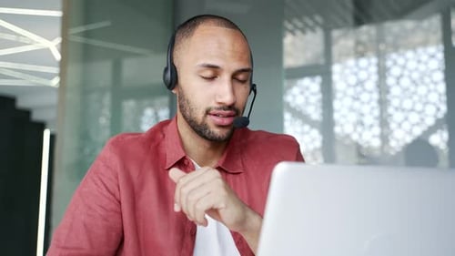 Businessman in headset talking on a video call conference using laptop in office. Manager