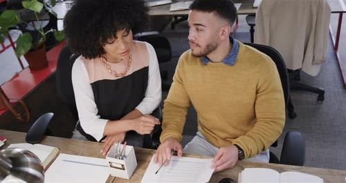 Divers collègues masculins et féminins assis au bureau, regardant l'ordinateur et parlant, au ralenti