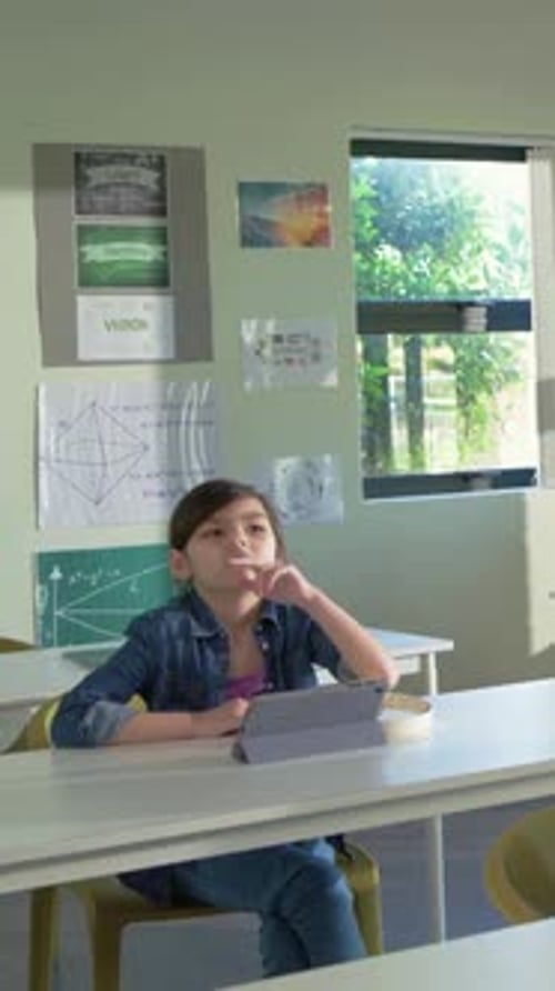 Vertical video: Tilting head, student in denim looking up in class, sunlight drawing gaze, tablet