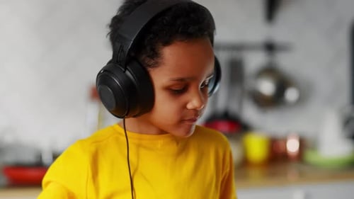 Child with Headphones Listening at Kitchen Counter