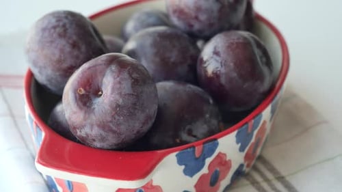 Stack of Plums in a Bowl on White Background