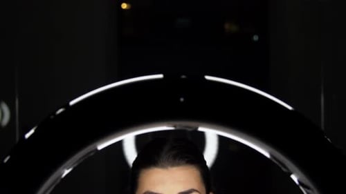 Woman Puts on Glasses in Front of Ring Light