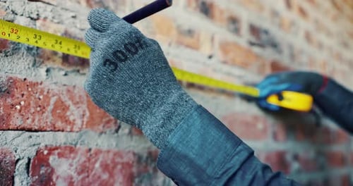 Hands, wall and tape measure at construction site for precision, dimension and layout for building