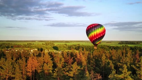 Dreamlike Landscape of Small Village Surrounded By Green Forest and Hot Air Balloon Flying Over It