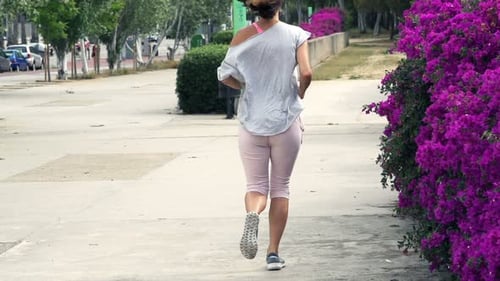 Young woman jogging in city park workout in super slow motion