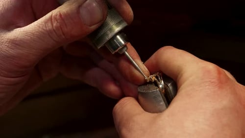 Erfahrener Juwelier, der einen Edelstein behutsam in ein Schmuckstück einarbeitet