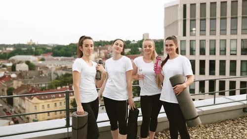 Femmes qui tintent des bouteilles de sport après un entraînement sur la terrasse