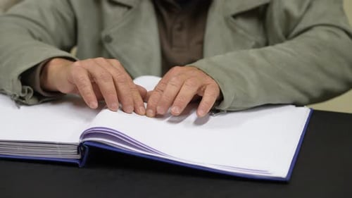 Close Up of Hands Reading Braille in Book