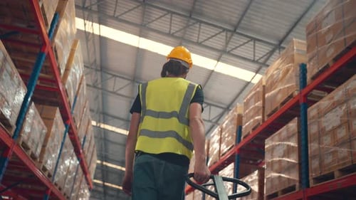 Man using hand pallet truck in large warehouse