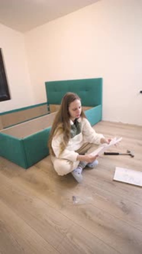 Femme vérifiant les instructions tout en construisant elle-même son lit