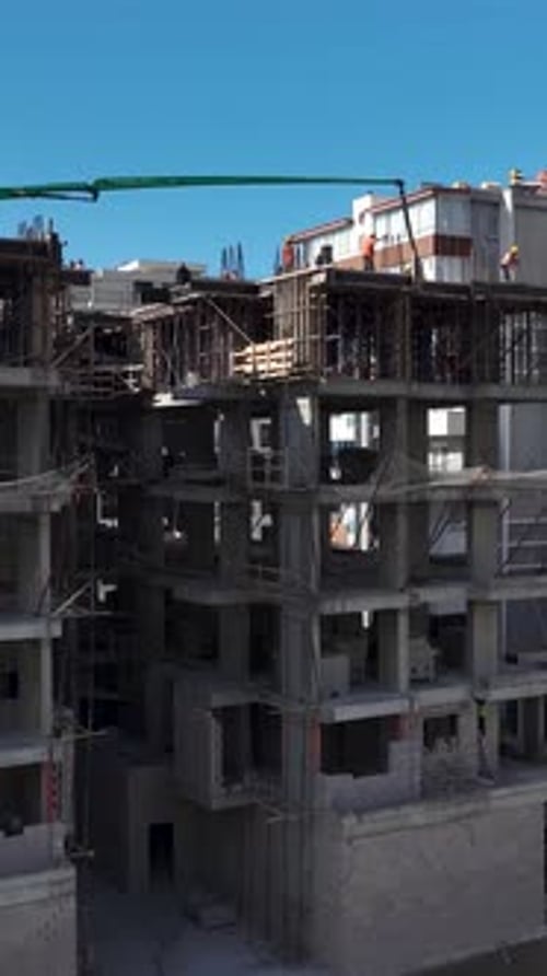 Vídeo vertical: proyecto residencial, sitio de construcción vivo con trabajadores vertiendo concreto para el