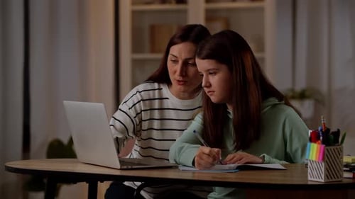 Woman Helps Teen Girl with Homework Indoors
