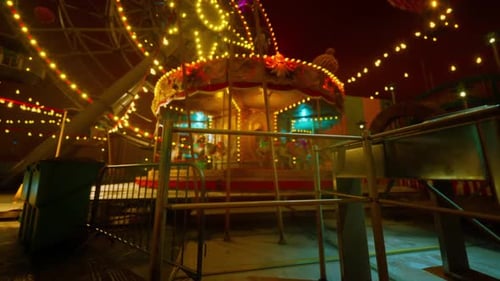 Empty Amusement Park at Night with Illuminated Rides and Quiet Atmosphere