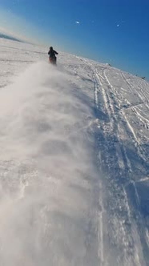 Snowmobiles Travel Across Snowy Mountain in Winter