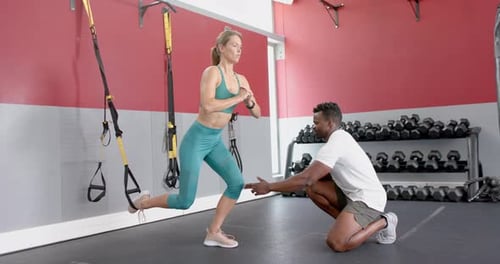 Fit young Caucasian woman trains with an African American man at the gym