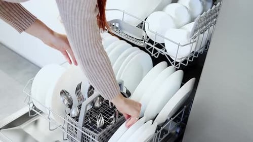 Woman Unloading Clean Dishes in Modern Kitchen