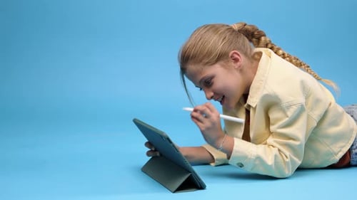 Girl Using Tablet Device, Lying on Floor