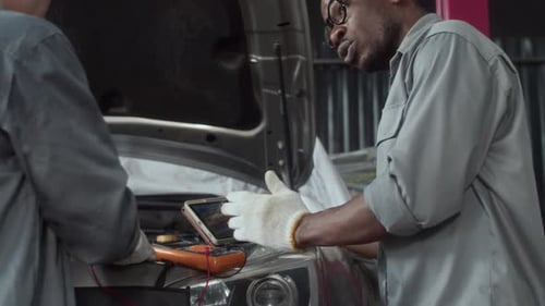 Compañeros de trabajo inspeccionando el trabajo del motor de un automóvil con un equipo especial