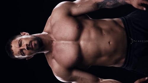 Muscular Man Posing Shirtless Against Black Background