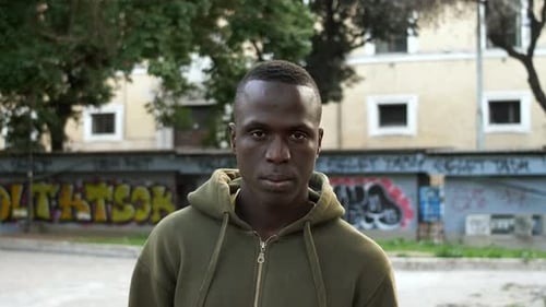 ernster trauriger junger schwarzer Mann starrt in die Kamera - urbaner Hintergrund