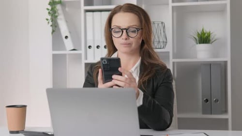 Woman Using Smartphone in a Modern Office