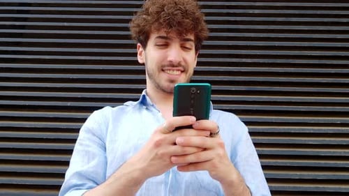 Carefree Young Man Chatting with Smartphone in a City