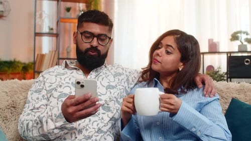 Indisches Familienpaar Mann Frau trinkt gemeinsam Morgenkaffee mit Smartphone Ruhiger Tagesbeginn