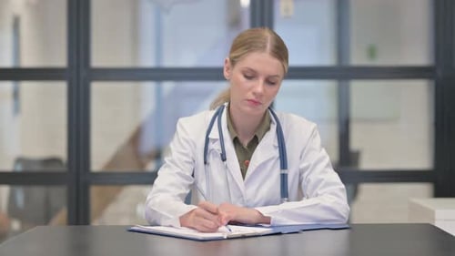 Lady Doctor Writing Medical Documents in Clinic