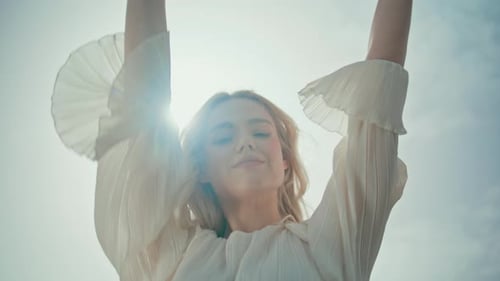 Blonde Woman Posing with Arms Raised to Sky