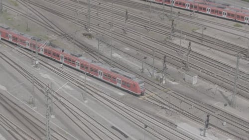 Roter Zug auf mehreren Bahngleisen an einem Bahnhof