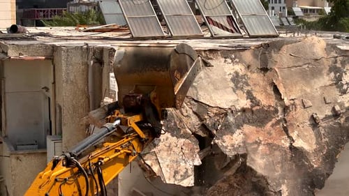 Excavator arm demolishing an old building, Aerial view