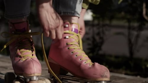 Roller Girl Ties Bright Yellow Shoelaces on Pink Roller Skates