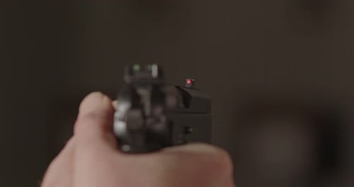 9-mm-Pistole, die auf etwas gerichtet ist. Die Frontscheibe der Pistole ist scharf