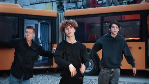 Young Male Dancers Performing Contemporary Street Dance Near Graffitied Urban Bus Showcasing Dynamic