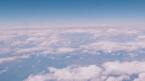 Flying over the clouds, view from the plane on a blue sky and cumulus clouds