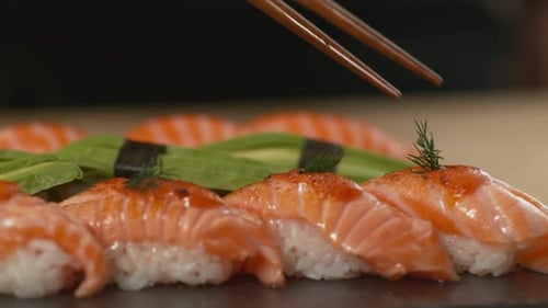 Hand picking delicious sushi rolls with chopsticks in a japanese restaurant