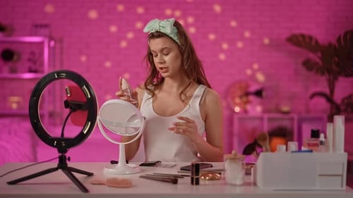 Young Woman Demonstrating Skincare Routine in Stylish Pink Studio