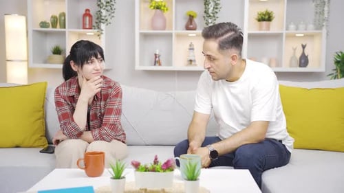 Couple Sitting on Sofa Looking Sad and Concerned