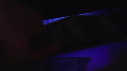 One Hundred Dollar Bills Being Inspected With Blue Light