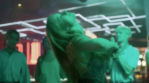 Group of Young Friends Dances Together in Neon Light of Night Club