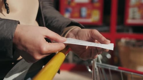 Woman Checks Paper Check After Shopping for Groceries