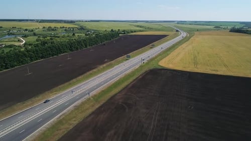 Aerial View of a Cars Driving Through Highway Road Among Agriculture Fields and Green Countryside